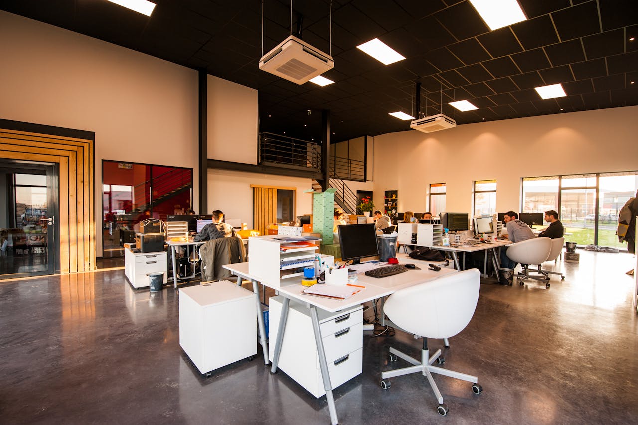 why-choose-us A spacious and modern open-plan office with natural lighting and employees working at desks.